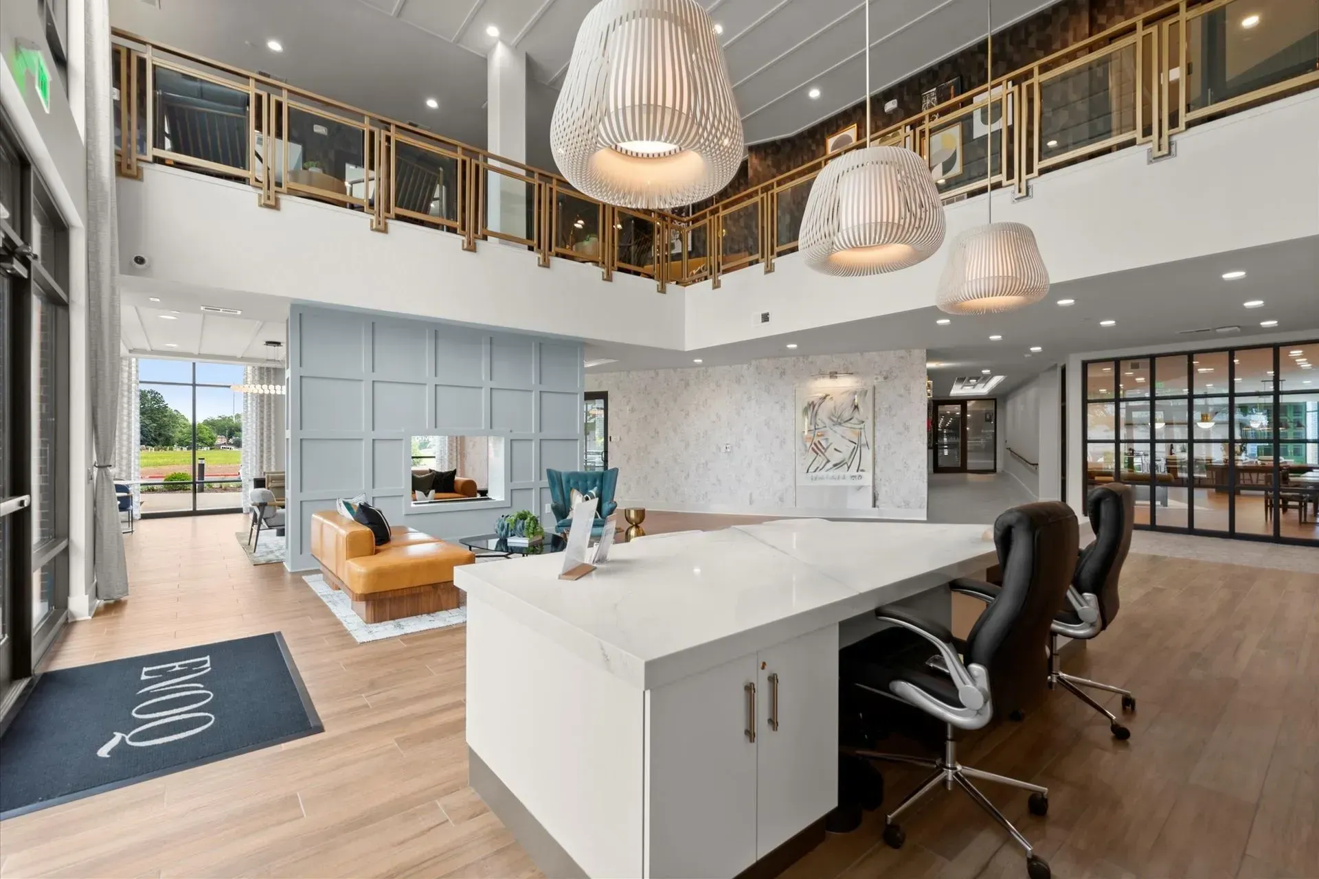 Bright modern lobby with white desk, high ceilings, large windows, and decorative hanging lights.