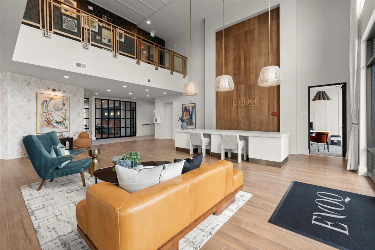 Lobby area with modern furniture, wooden paneling, and a mezzanine level.