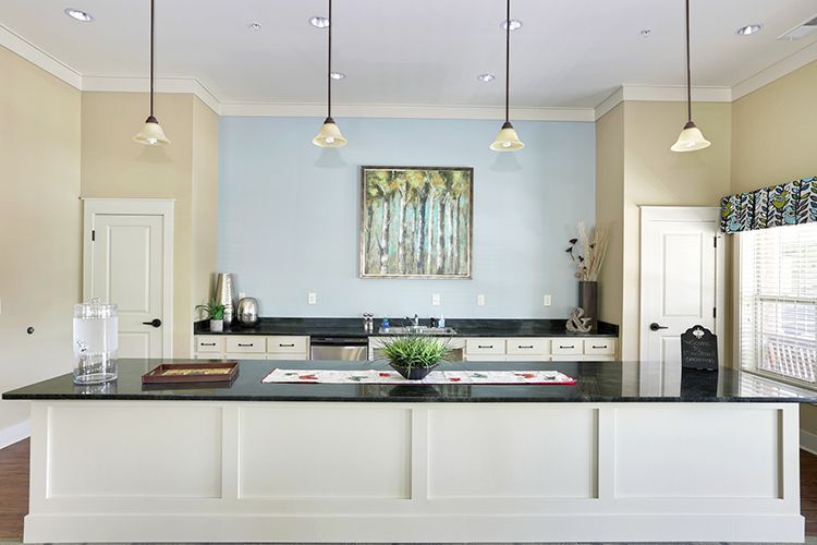Kitchen island with a black countertop, white cabinets, and pendant lights.