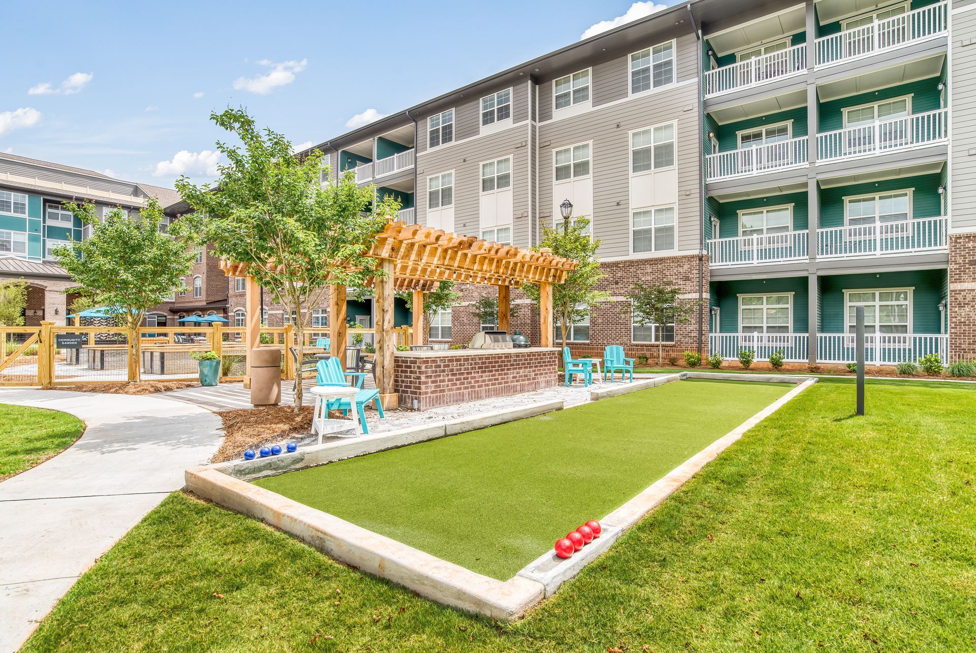 Apartment complex with a winding sidewalk through a grassy area, clear sky.