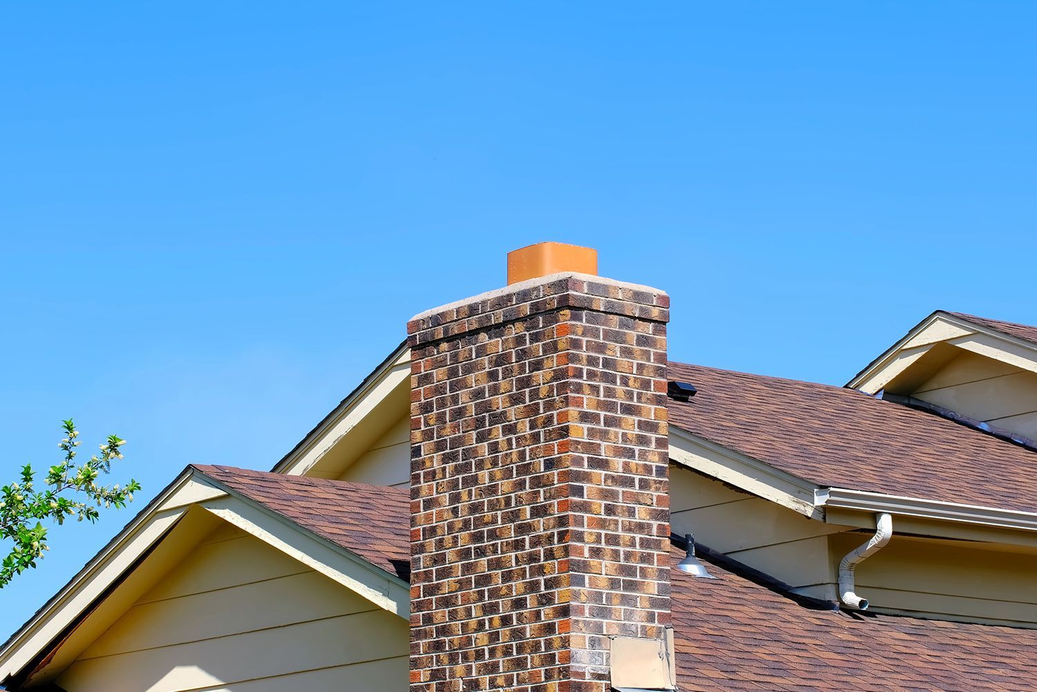 A chimney on the roof of a house with a blue sky in the background.