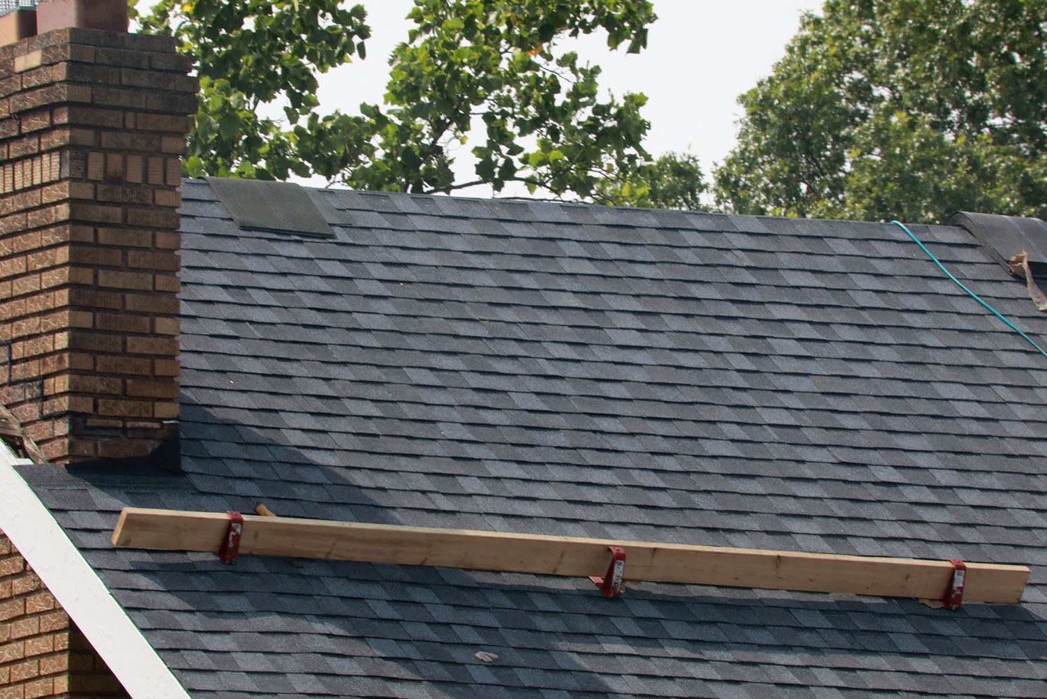 A roof with a chimney and a piece of wood on it