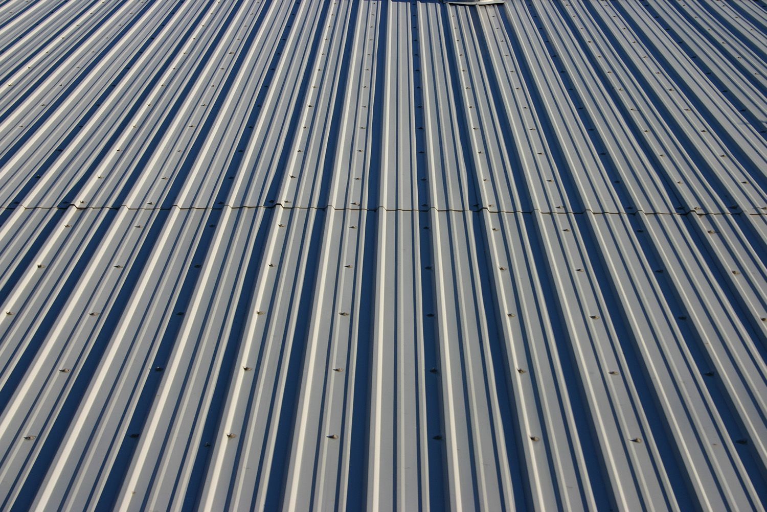 A close up of a metal roof with a blue sky in the background