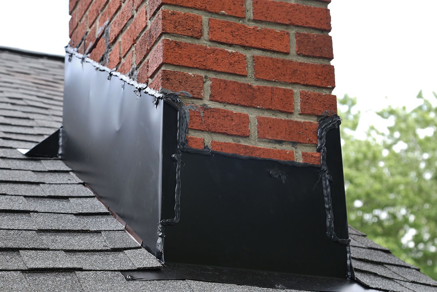 A brick chimney is sitting on top of a roof.