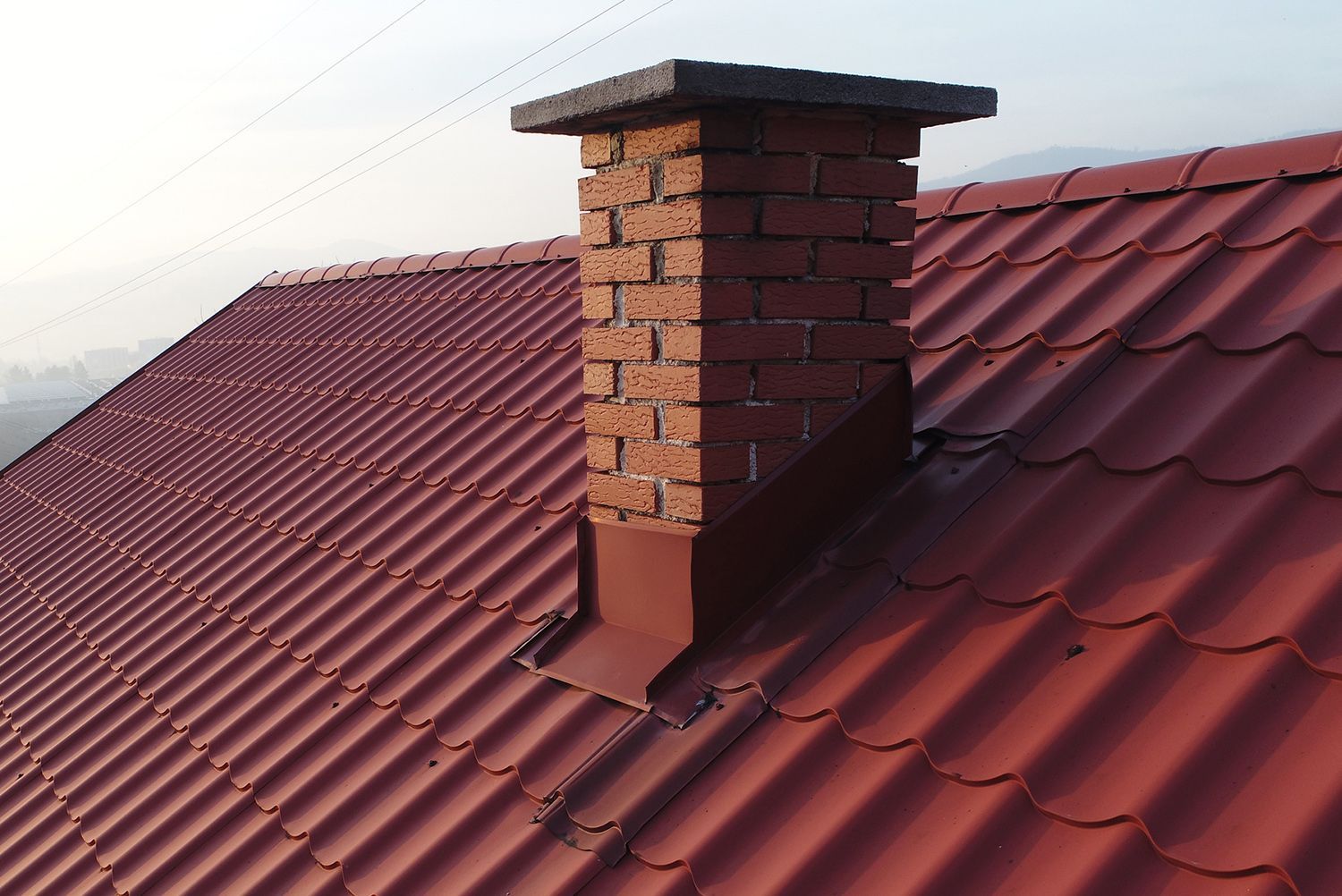 A brick chimney on top of a red roof