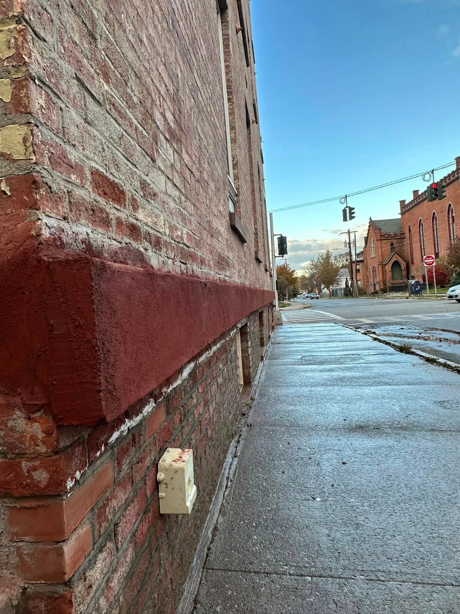 A sidewalk next to a brick building on a rainy day.
