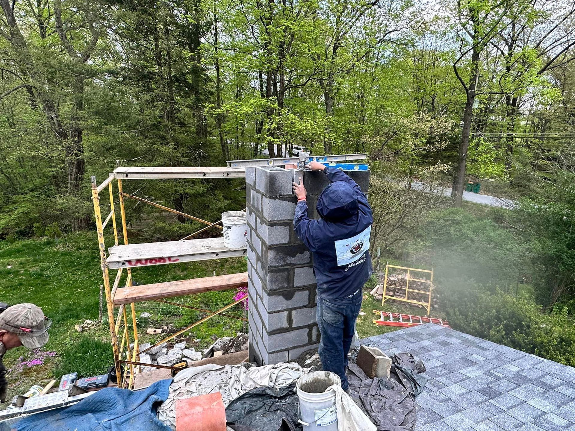A man is working on a chimney on top of a roof.