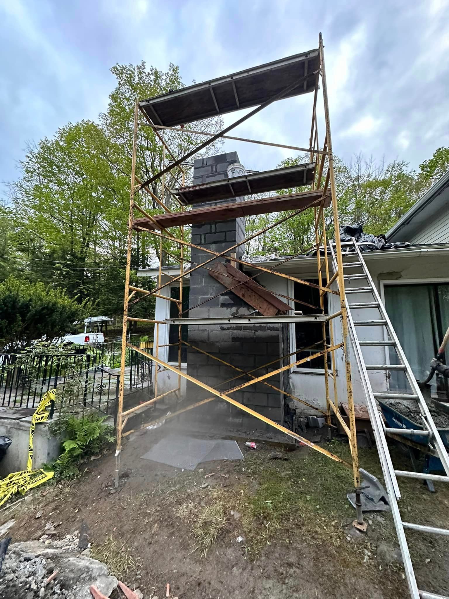 A scaffolding is being used to remove a chimney from a house.