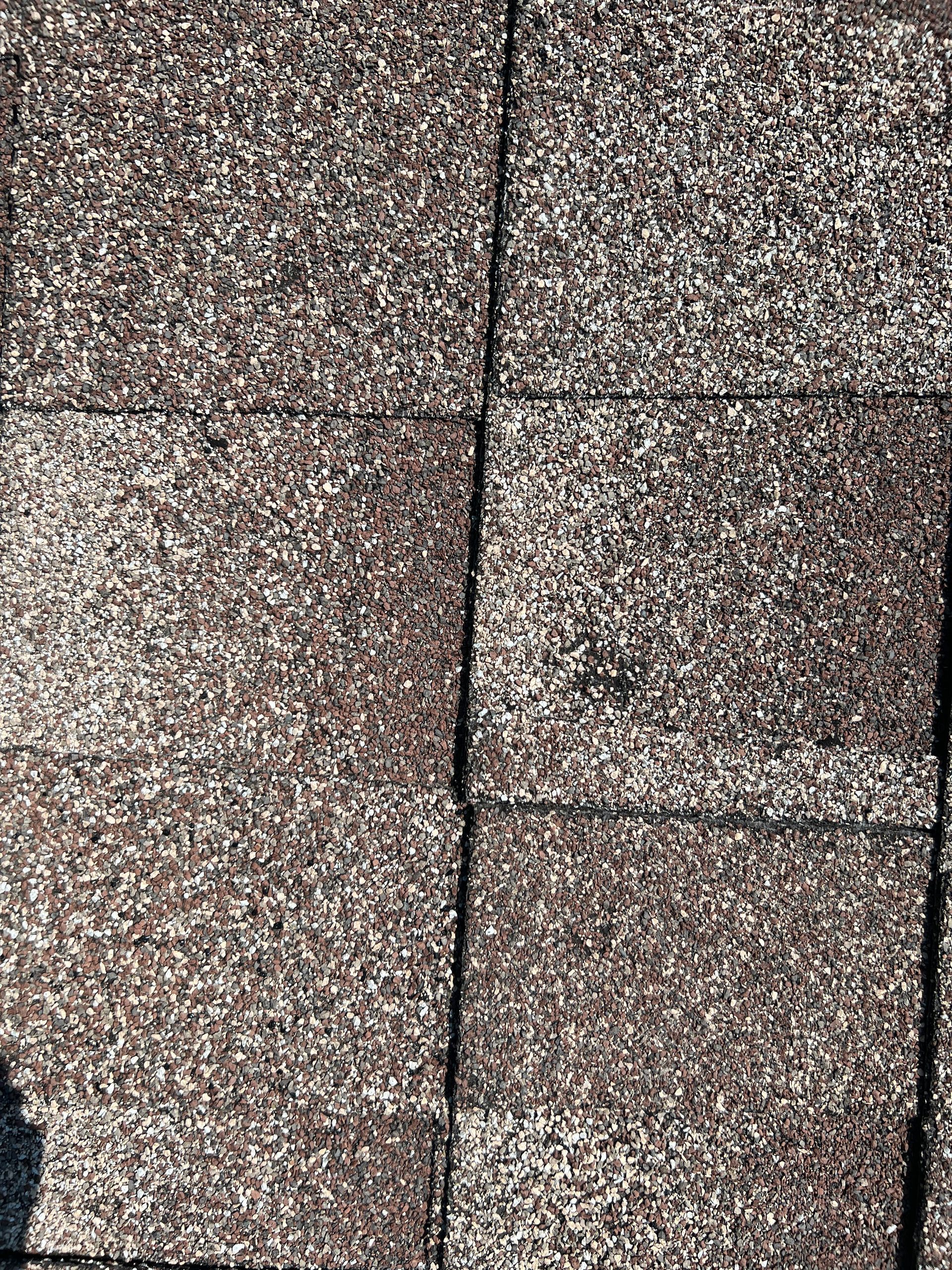 A top-down view of dark brown textured asphalt roofing shingles with a visible grid pattern.