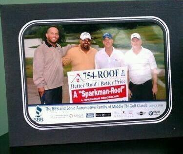 Four people pose at a golf tournament holding a sign for 