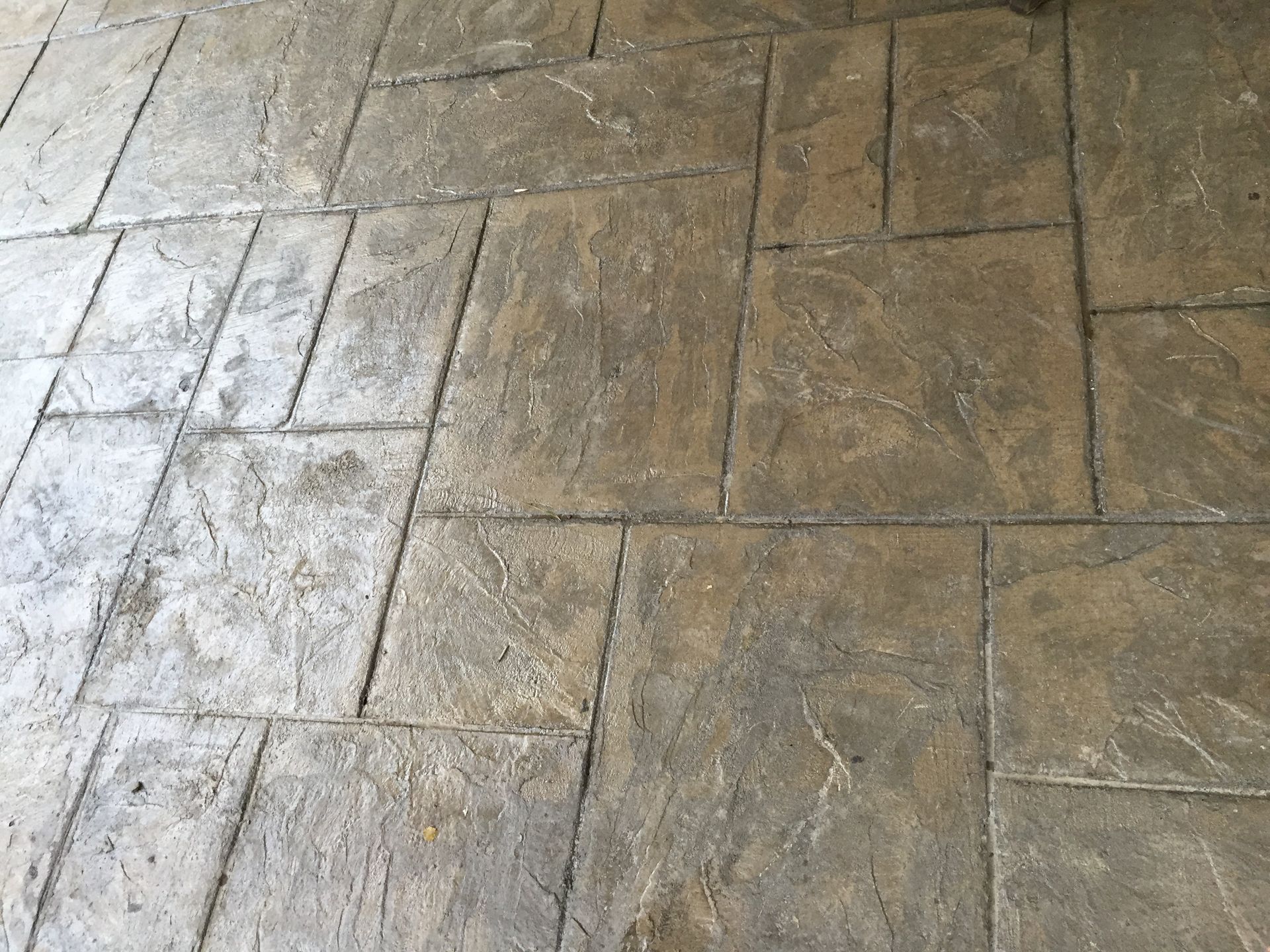 Tan, textured stamped concrete patio with a rectangular, stone-like interlocking tile pattern.