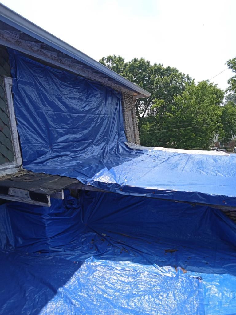 Blue tarps draped over a flat roof and against an exterior wall for protection or temporary repair.