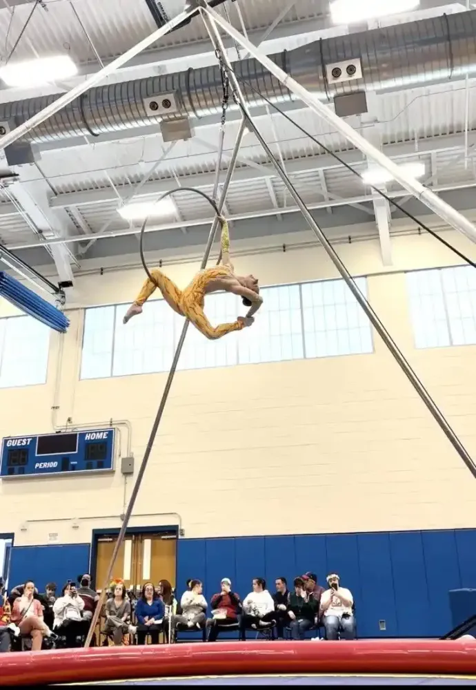 A gymnast is doing a trick on a hoop in a gym.