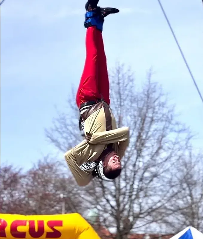 A man is doing a handstand in front of a sign that says circus