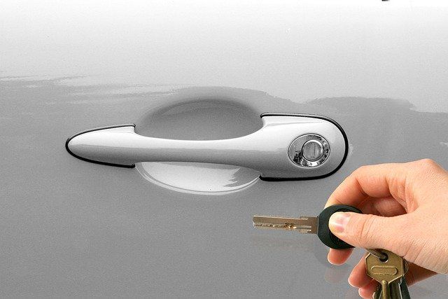 A person is holding a car key in front of a car door