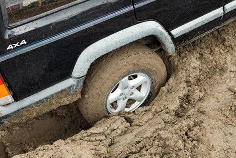 A black jeep is stuck in the mud.