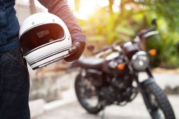 A person is holding a helmet in front of a motorcycle.