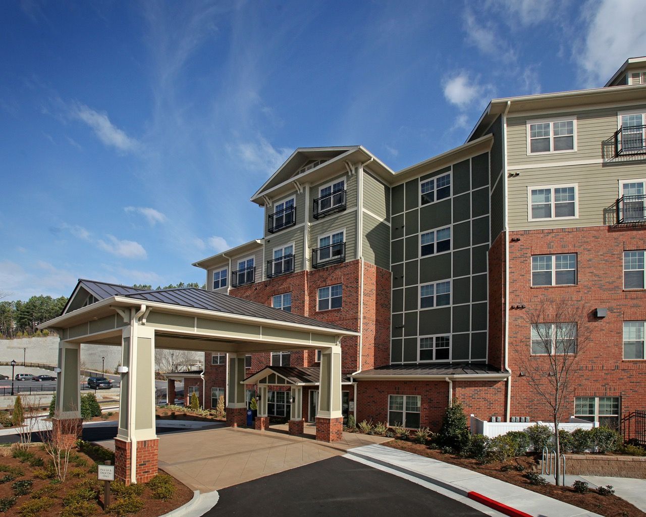 Exterior view of a modern apartment building with brick and beige siding and a covered entrance.