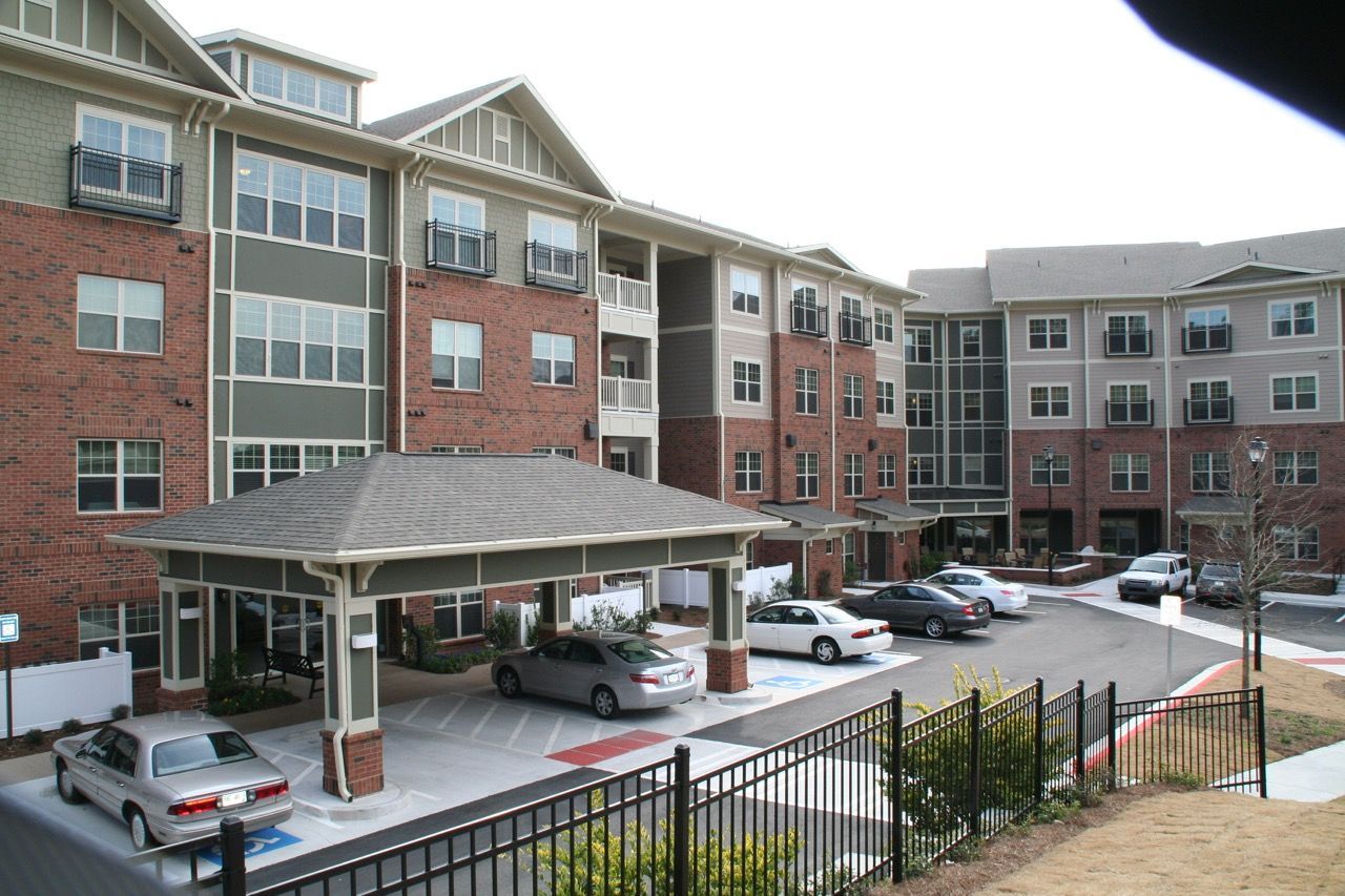 Exterior view of a multi-building apartment complex with a covered entrance and parking area.