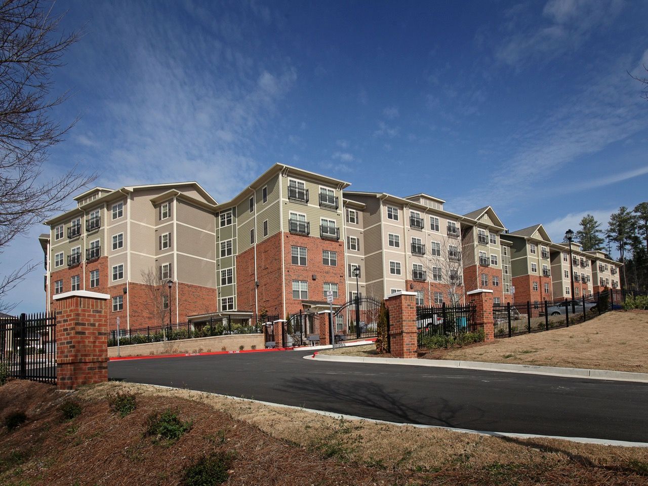 Exterior view of a modern apartment complex with brick accents and a gated entrance.