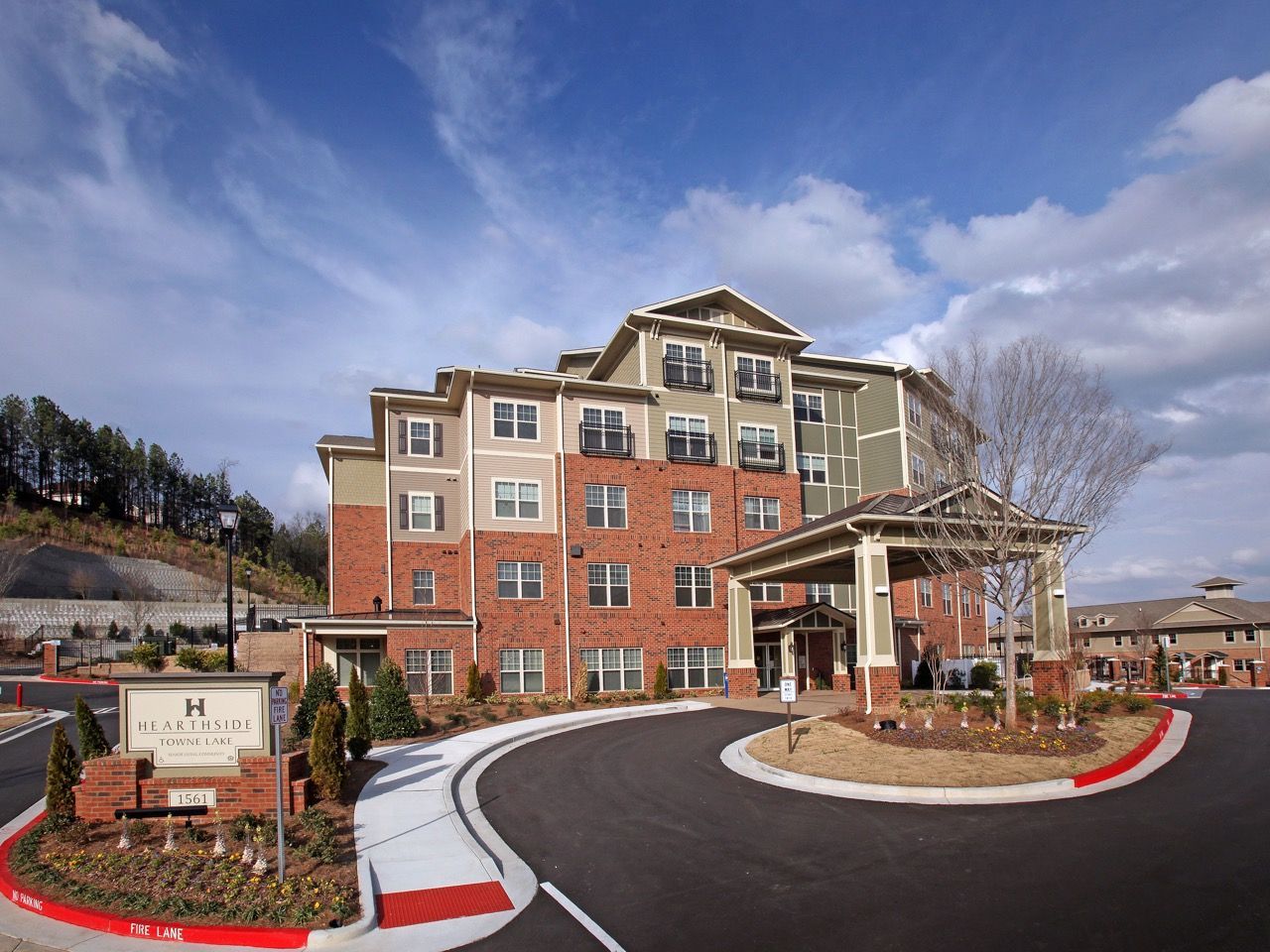 Exterior view of a modern apartment building with a curved driveway and landscaped entrance.