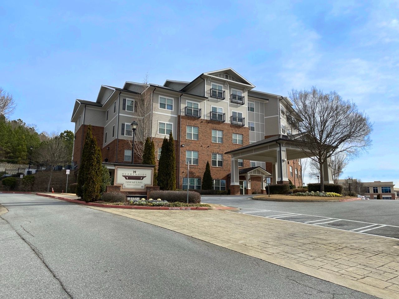 Exterior view of a multi-story apartment building with a covered entry and landscaped grounds.