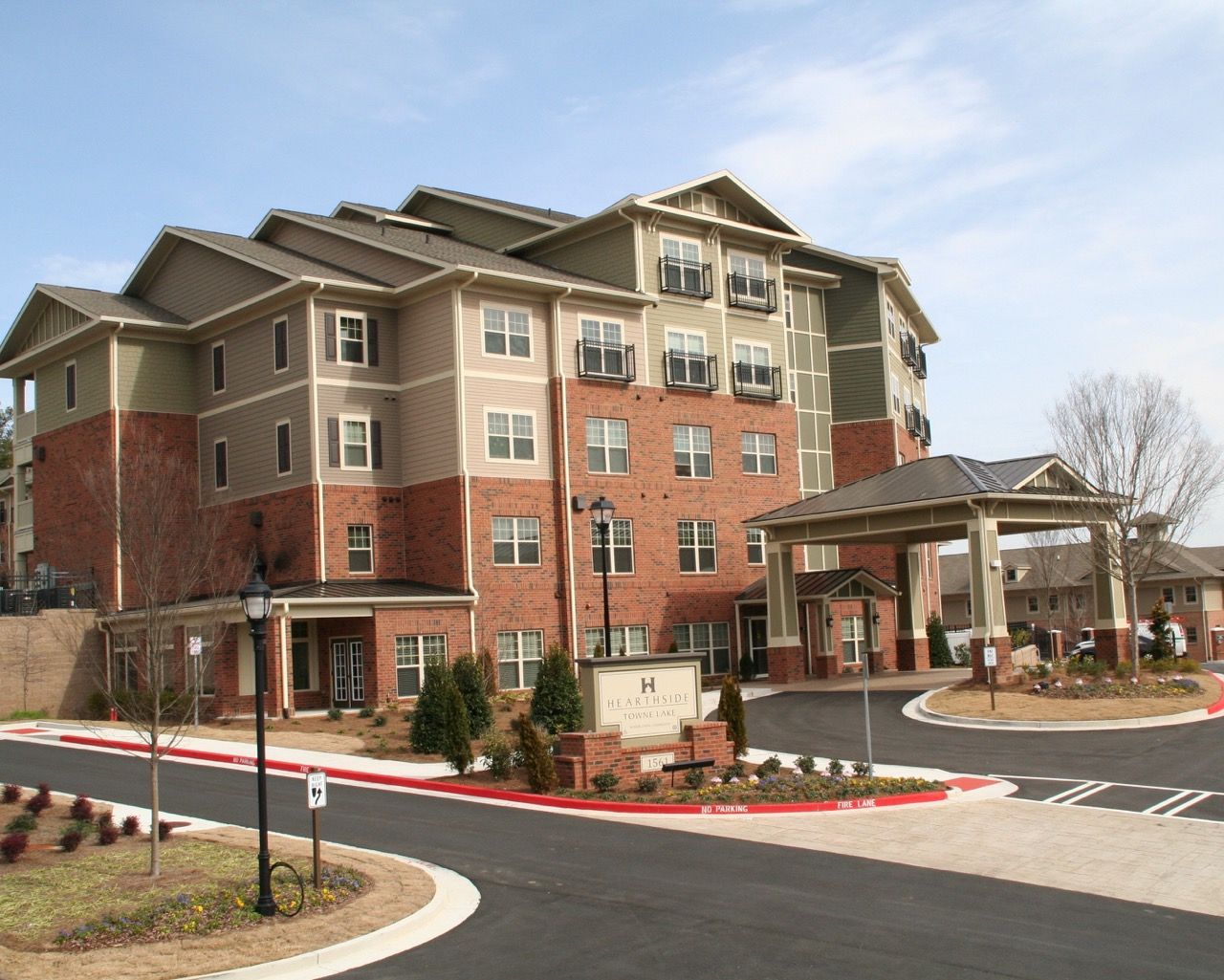 Exterior view of a multi-story apartment building with brick lower level, beige siding, and a covered entry.