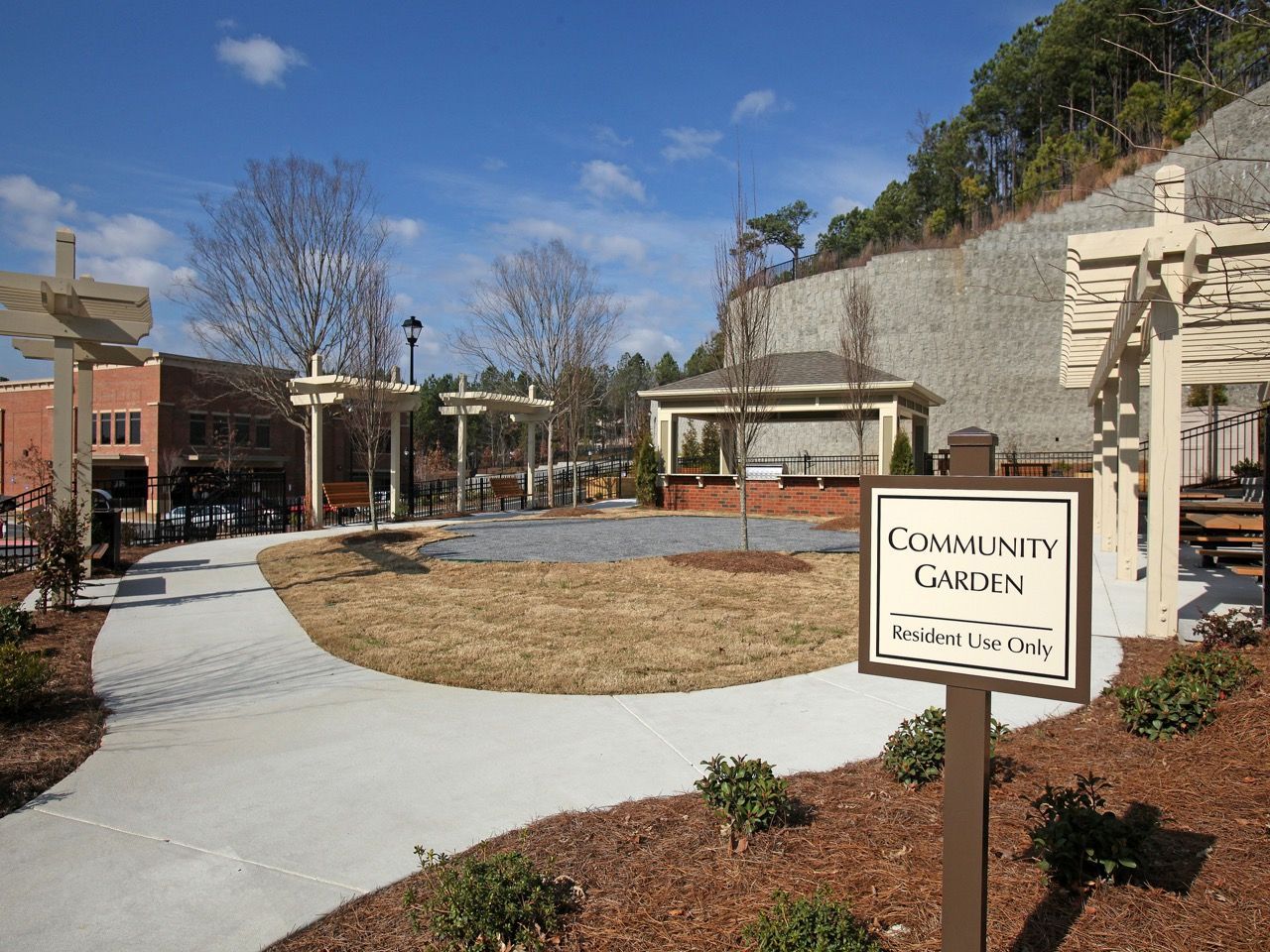 Outdoor community garden space with a curved concrete path and a sign reading 'Community Garden'.