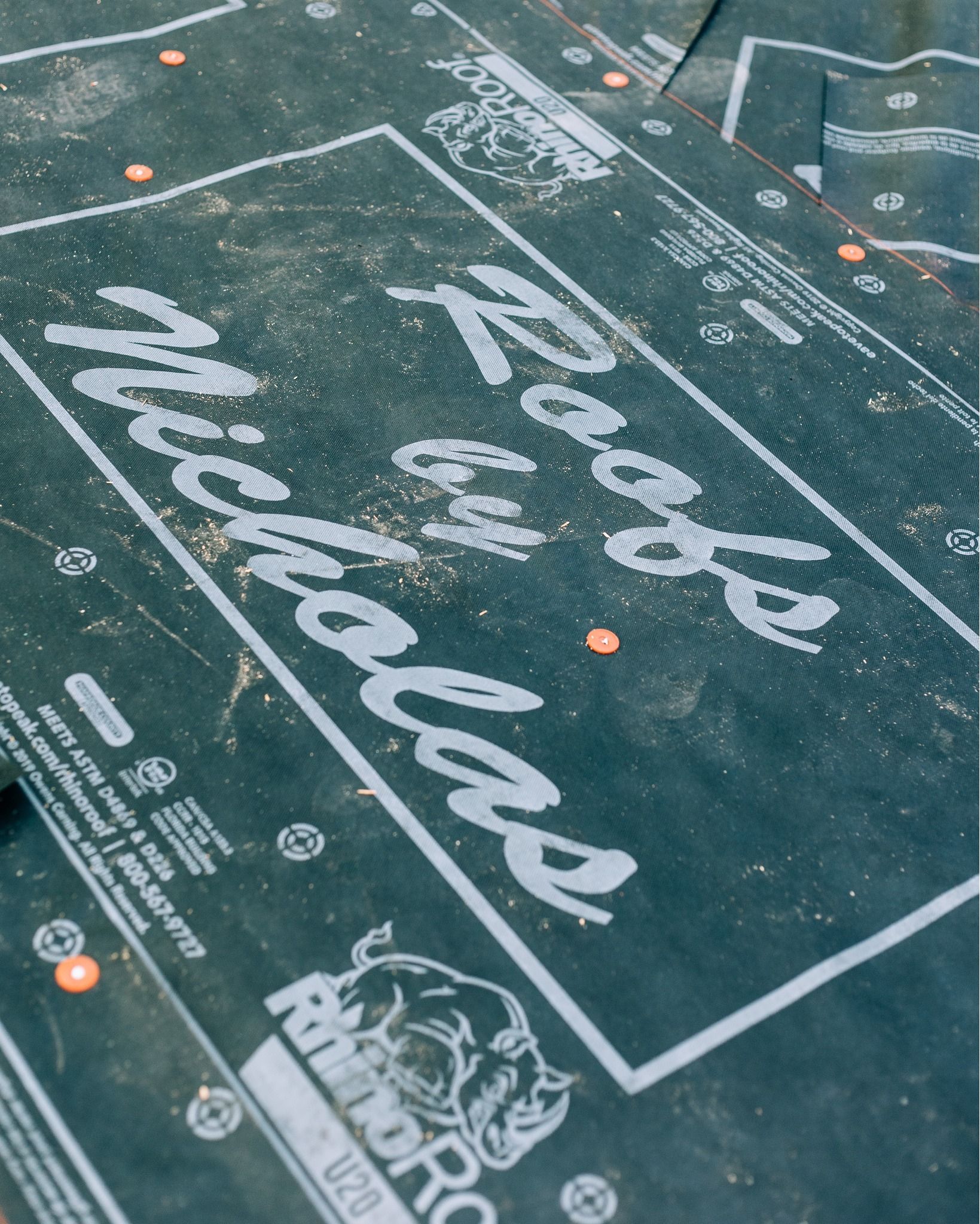 Close-up of Roofs by Nicholas branded roofing underlayment installed on residential roof