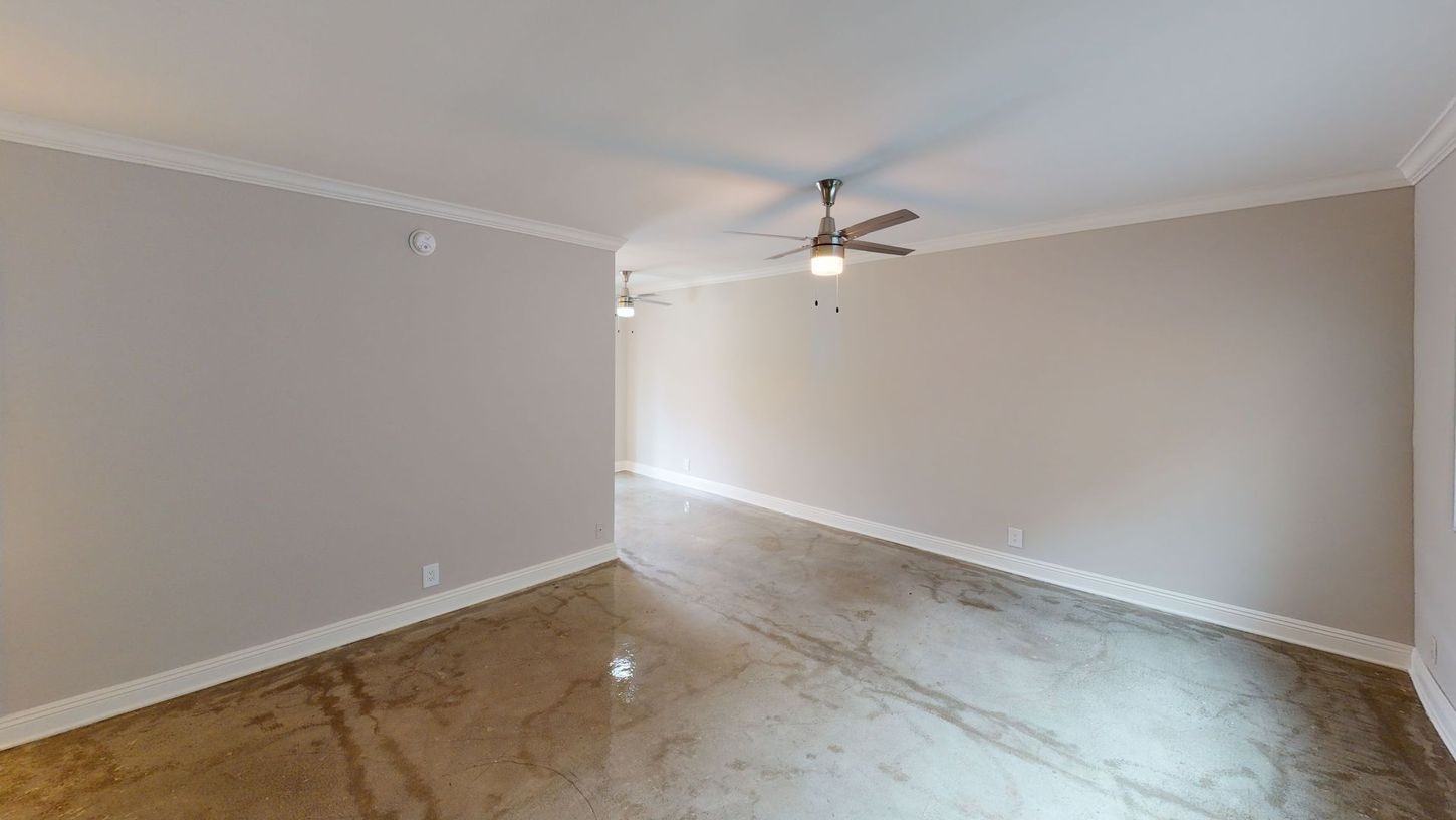 Empty room with polished concrete floor, ceiling fans, and neutral-colored walls.