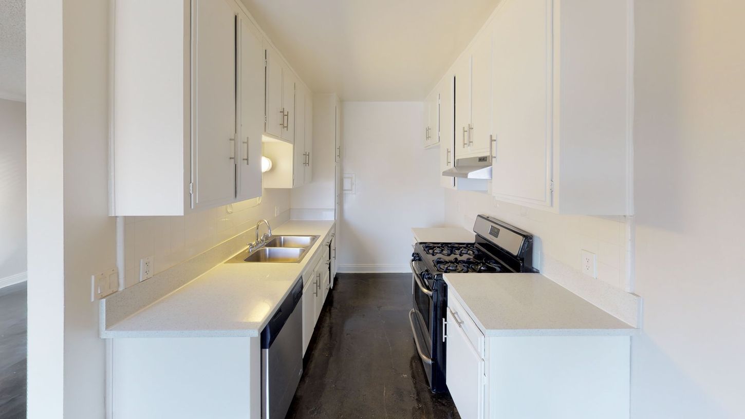 White kitchen with cabinets, countertops, and appliances in a narrow space.