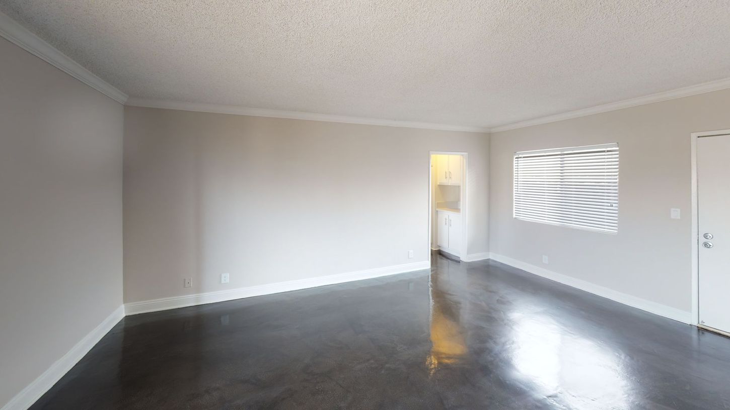 Empty room with gray walls, dark floor, and a bright doorway.