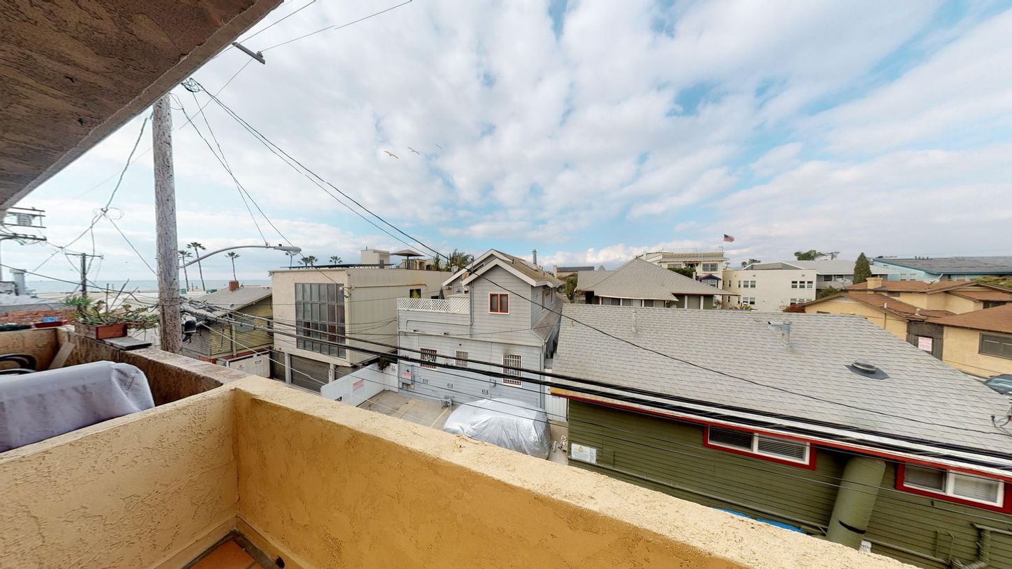 View from a balcony overlooking a coastal neighborhood and cloudy sky.