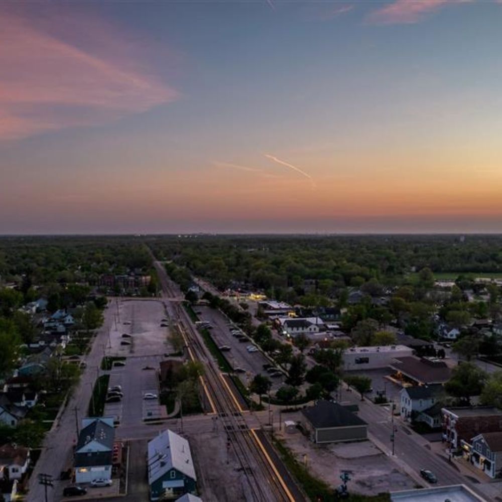 Brick building with tower, windows, and trees in the foreground.