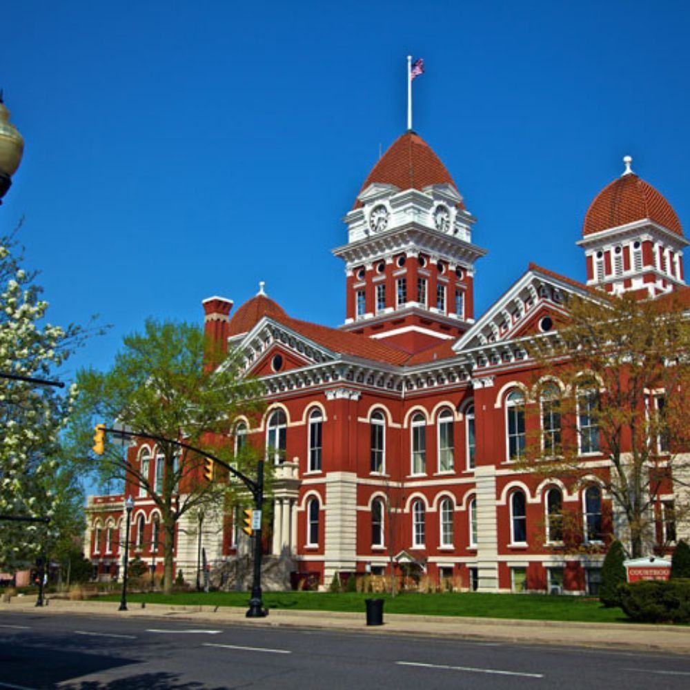 Brick building with tower, windows, and trees in the foreground.