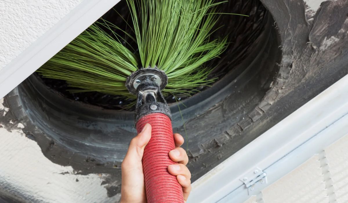 Eco Friend Carpet Clean - Person cleaning a dark circular vent with a brush.