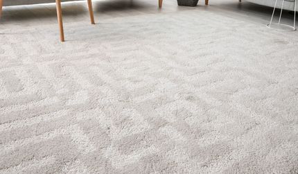 Eco Friend Carpet Clean - Light gray carpet with a subtle, zig-zag pattern, under furniture legs.