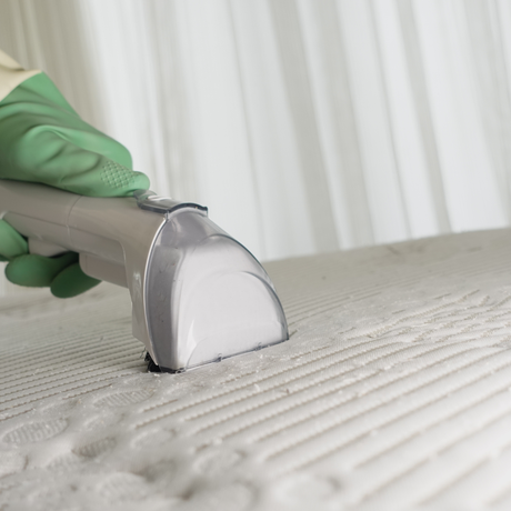 Eco Friend Carpet Clean - A gloved hand uses a handheld cleaner to clean a white mattress.