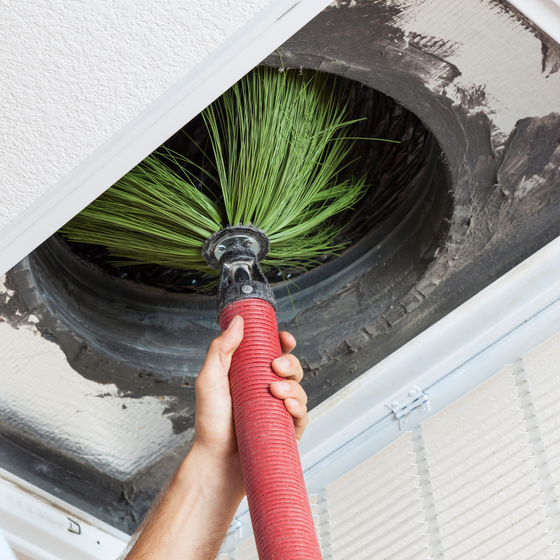 Eco Friend Carpet Clean - Person cleaning an air vent with a brush. Red hose, green brush, white ceiling.