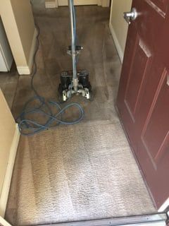 A vacuum cleaner is sitting on a carpet in a hallway next to a door.