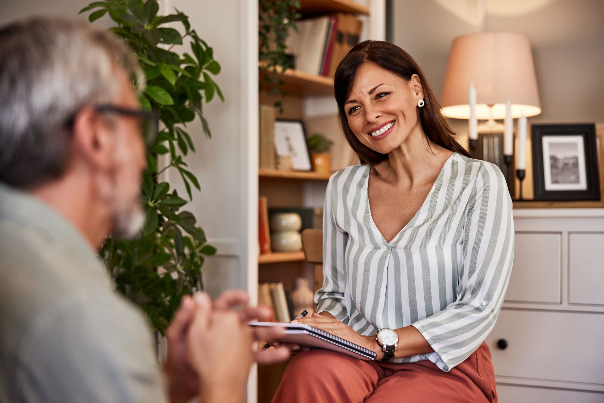 A woman is sitting in front of a man and talking to him.