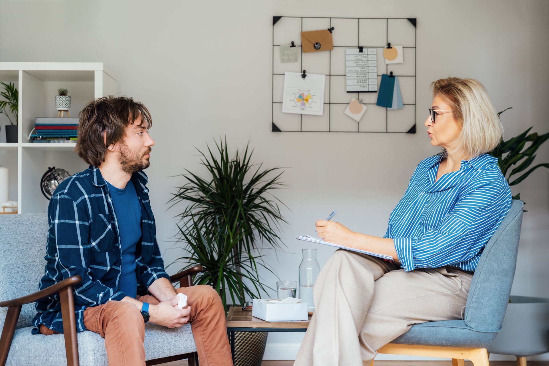 A woman is sitting in a chair talking to a man in a living room.