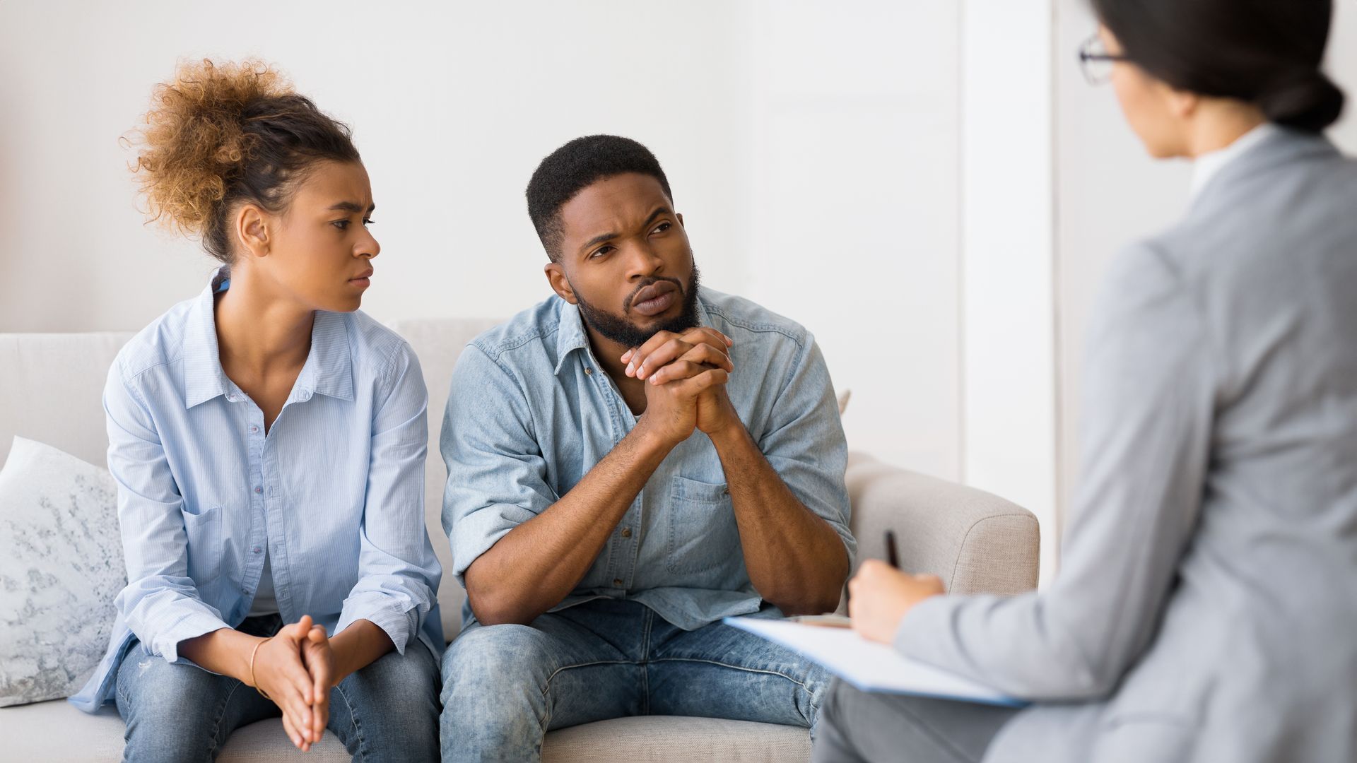 A man and a woman are sitting on a couch talking to a woman.
