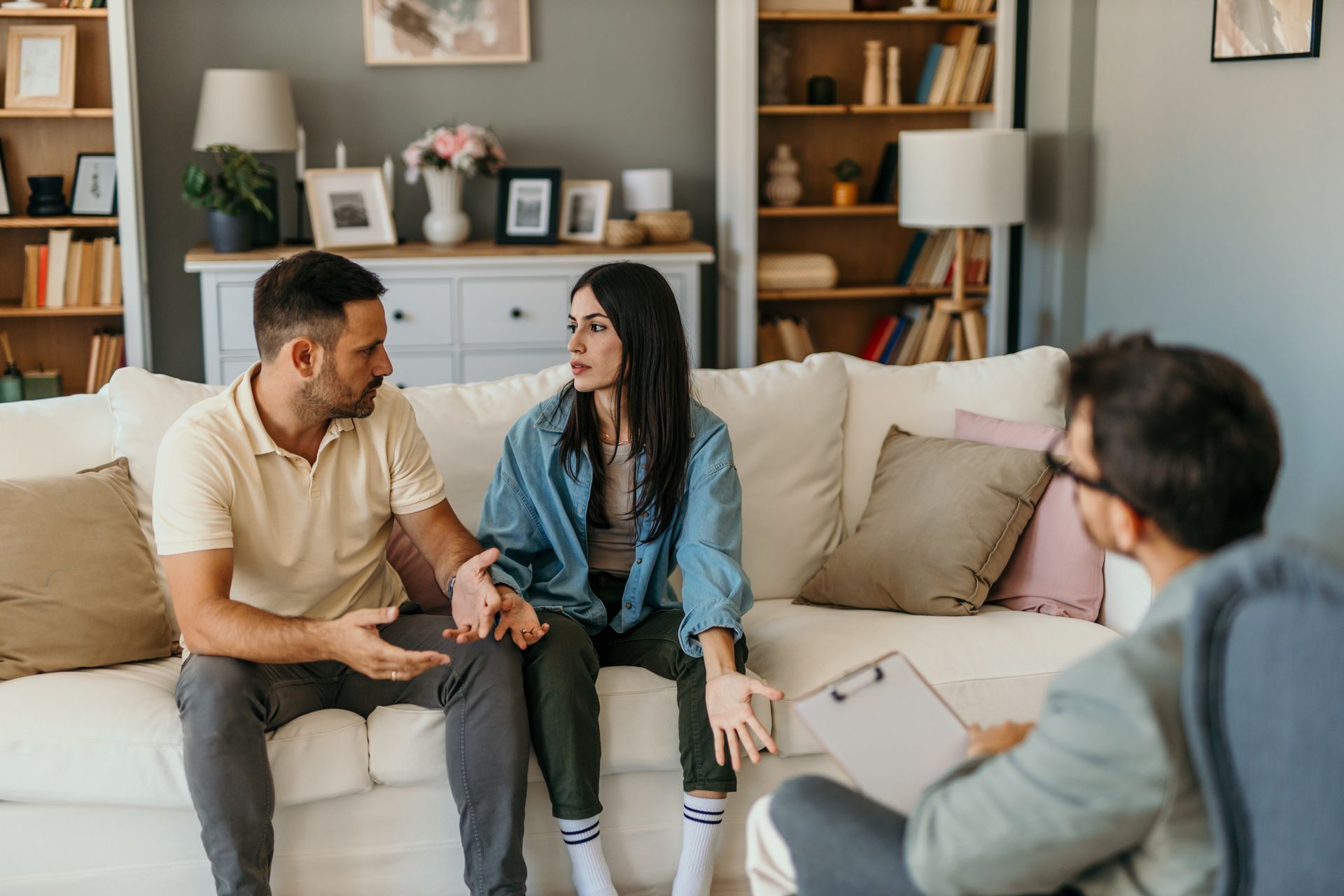 A man and a woman are sitting on a couch talking to a man.