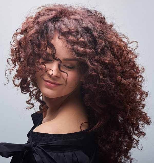 A woman with long curly hair is wearing a black shirt