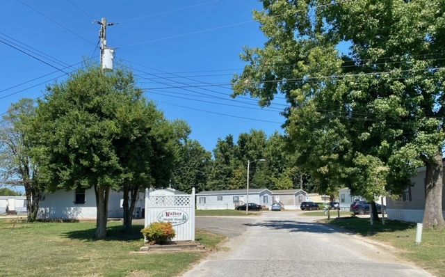 A man is shaking hands with another man while holding a hard hat.