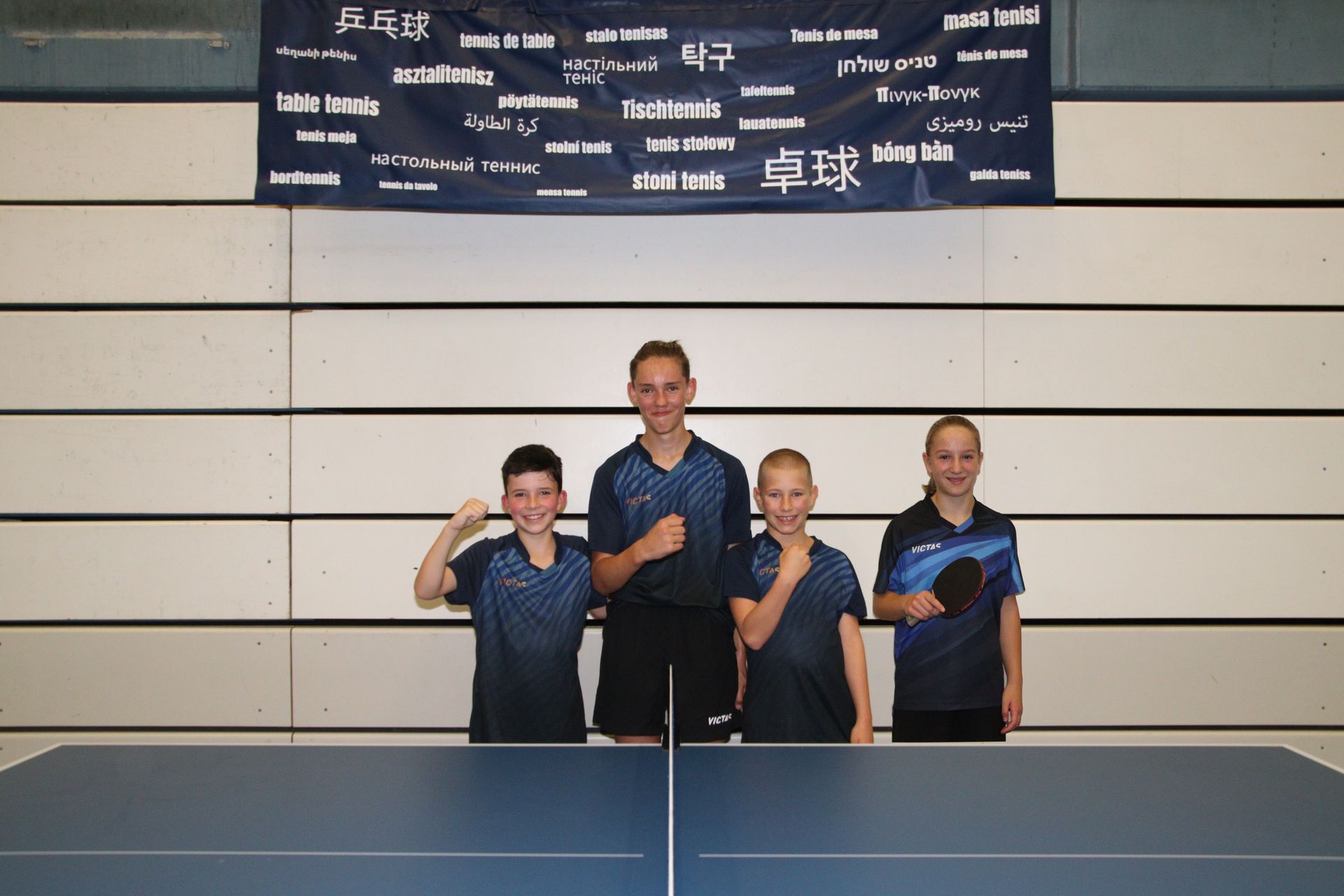 Eine Gruppe von jungen Jungen steht um einen Pingpong-Tisch herum