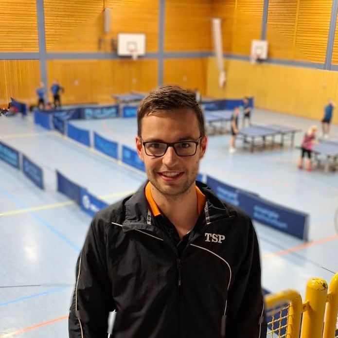 Ein Mann mit Brille und einem T-Shirt mit der Aufschrift Victas