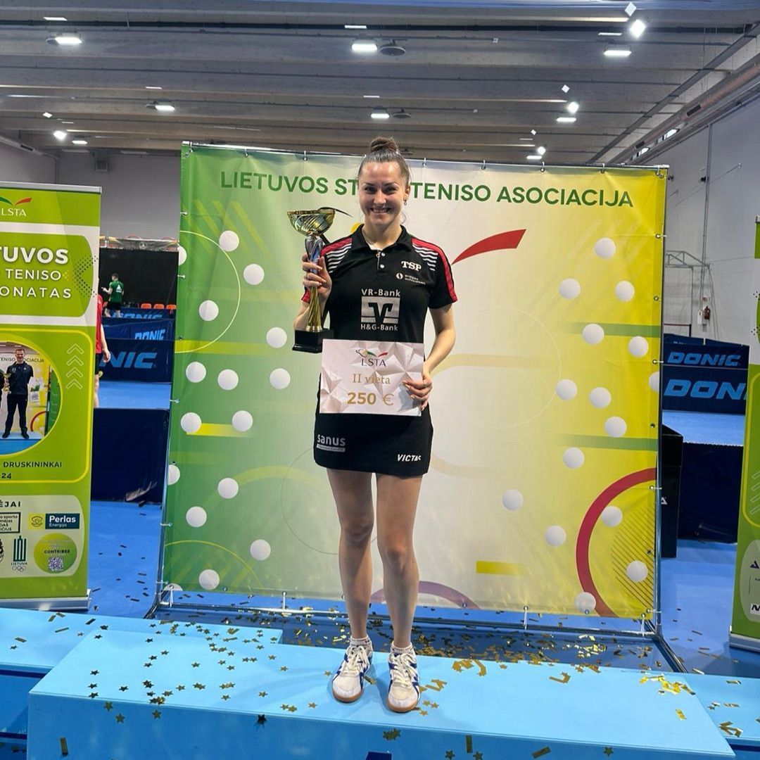 Eine Frau steht auf einem Podium und hält eine Trophäe in der Hand