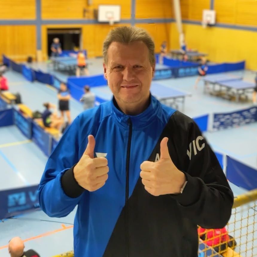 Ein Mann trägt ein blau-schwarzes Hemd mit dem Wort Victas darauf